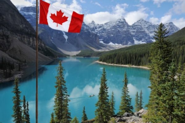 The Canadian National flag set against the Rocky Mountains of Banff National Park

Canada
